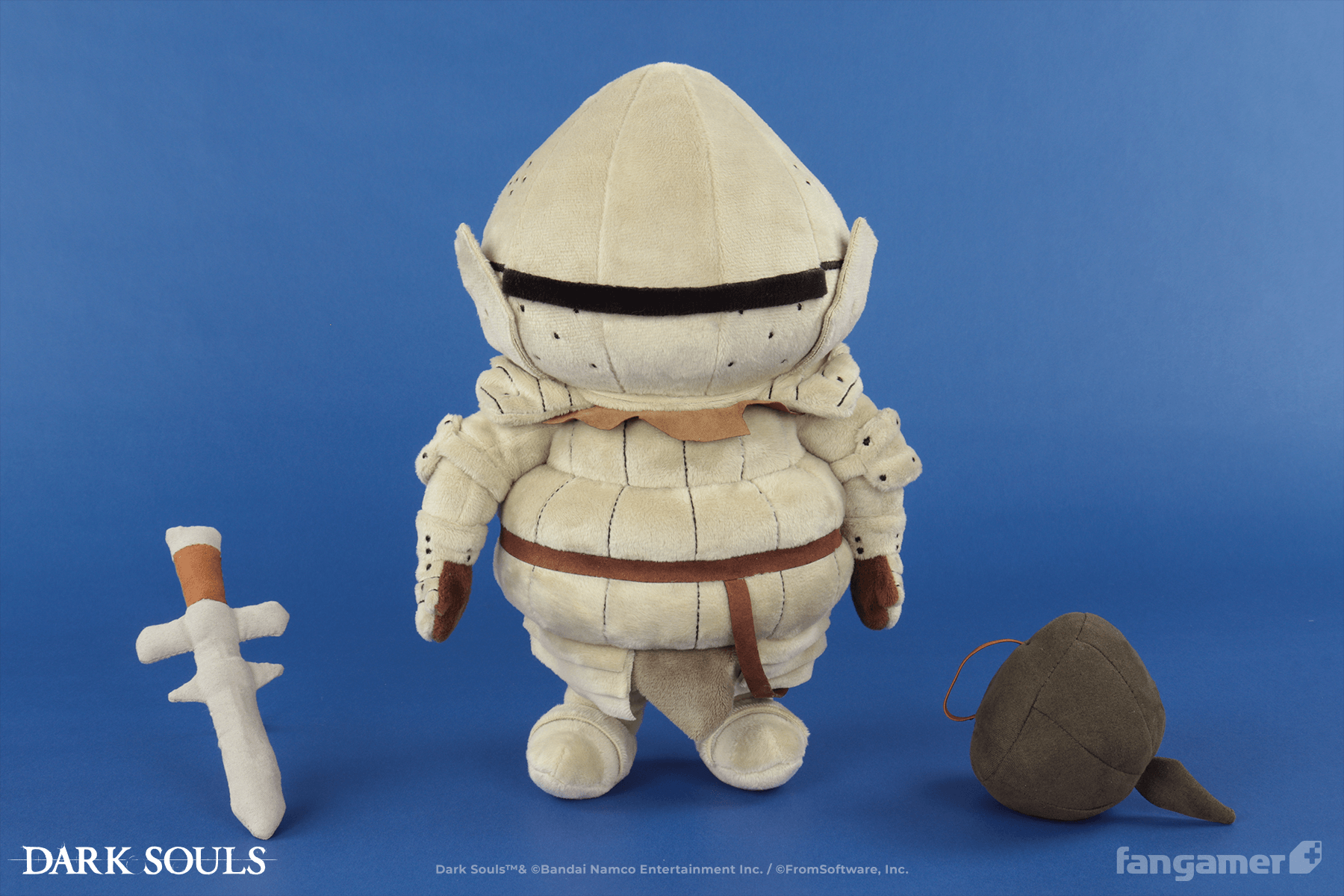 The official Siegmeyer plush photographed against a blue background. It's standing next to its plush sword and shield accessories, which are resting on the ground. 